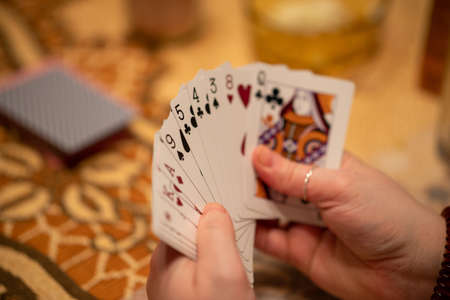 A selective focus of a hand of playing cards held by a person with a blurry background