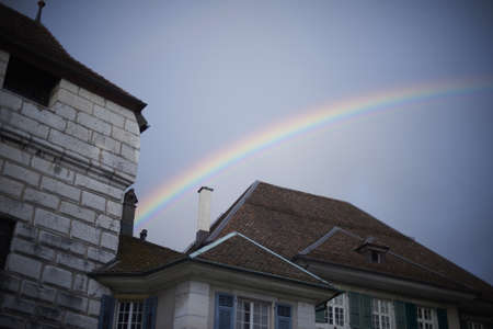 A low angle view of colorful buildings with a rainbow on the background under a blue skyの写真素材