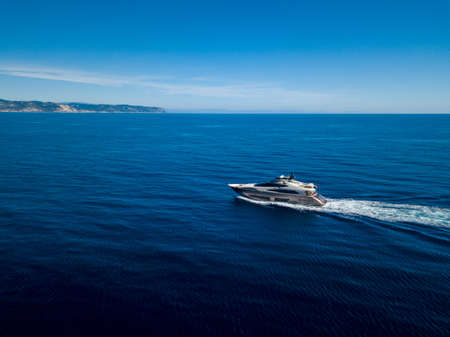 A high angle shot of a yacht sailing on the sea under a blue sky