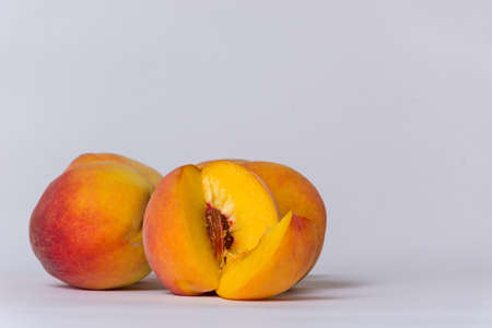 A cut sliced and a whole peach on a white backgroundの写真素材