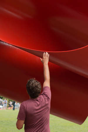 A vertical shot of a person standing near a huge red slide in an attraction park