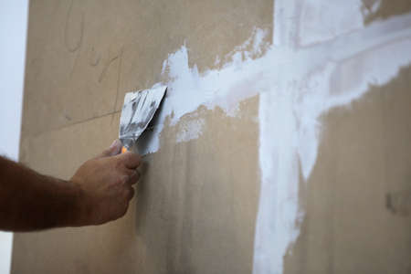 man putting putty on wooden wallの写真素材