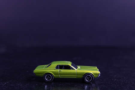 A selective focus shot of a light green toy car on a black surfaceの写真素材