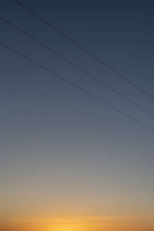 A vertical picture of a blue sky with wires during sunset - a cool picture for backgrounds