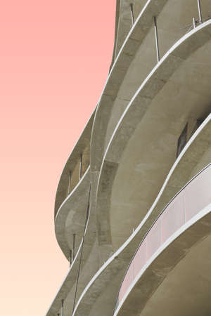 A vertical low angle shot of a white concrete building with a pink backgroundの写真素材