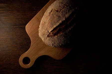 A high angle shot of freshly baked bread on a chopping board on a wooden surface