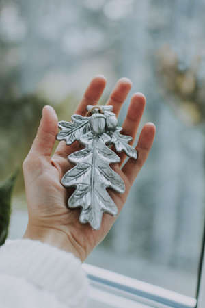 A vertical shot of a person holding a Christmas tree ornament