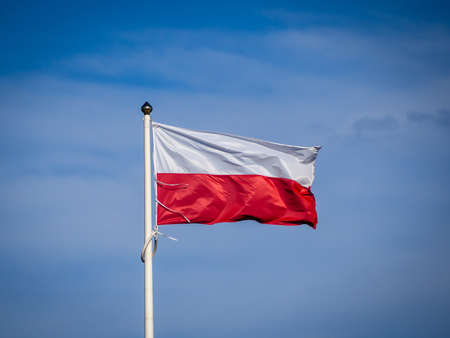 The red and white Polish flag with a clear blue sky on the backgroundの写真素材