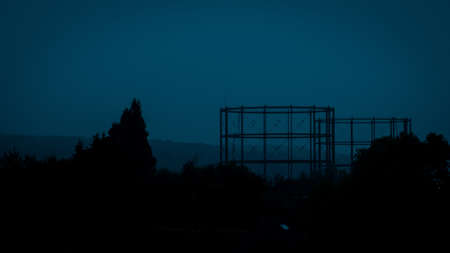 The silhouettes of trees and an iron contruction with a dark blue backgroundの写真素材