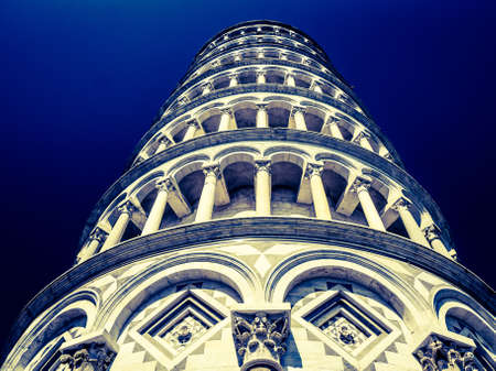 A low angle shot of the famous Leaning Tower of Pisa with a dark blue backgroundの写真素材