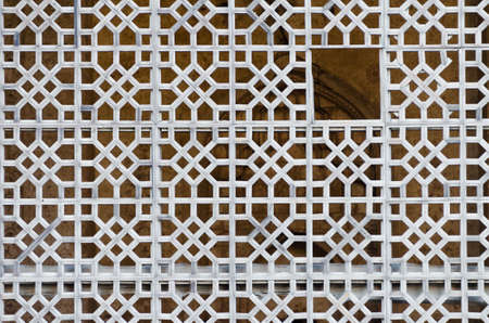 A white patterned fence against a mosque in the Central Asia
