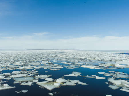 The pieces of ice in the frozen lake under the bright sky in winterの写真素材
