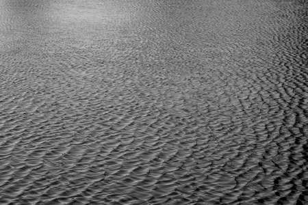 A grayscale shot of a sea with small waves