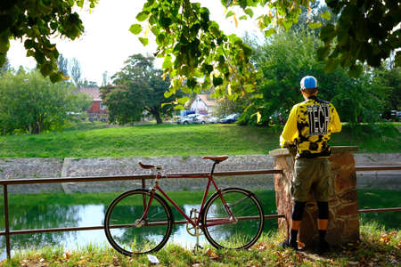 a bicycle near a river and a bench under a tree in italyの写真素材