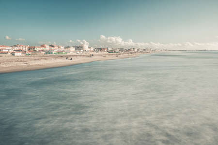 A cityscape with a lot of buildings on the shore near the sea under the cloudy skyの写真素材