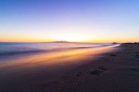 A beautiful scenery of the beach at the sunset with footprints on the sandの写真素材