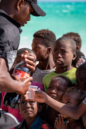 AMBATOMILO, MADAGASCAR - Aug 15, 2019: Kids are waiting in line for a cup of soda drinkのeditorial素材