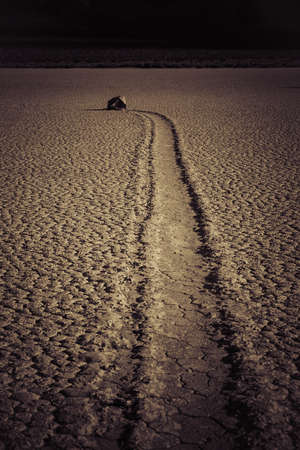 A vertical shot of a deserted ground of sand surrounded by a mountainous scenery