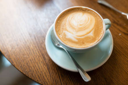 A high angle shot of a cup of cappuccino on a wooden surfaceの写真素材