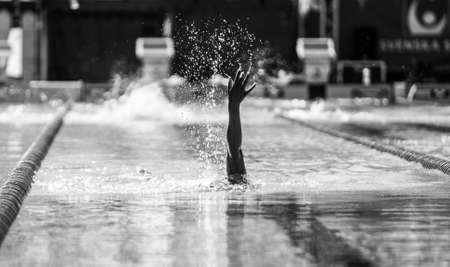 A greyscale shot of a hand of a swimmer during a swimming competitionの写真素材