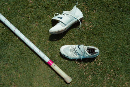 A high angle shot of sports shoes and a baseball batの写真素材