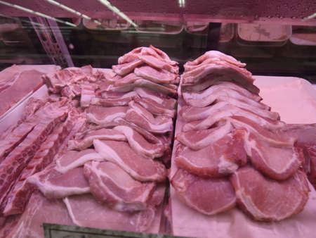 The trays of raw meat in the fridge in a butcher's shopの写真素材
