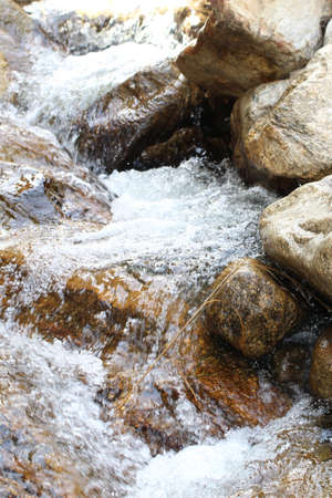 A vertical shot of the river rushing through the big stones