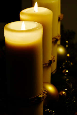 A closeup of candles surrounded by Christmas decorations against a black backgroundの写真素材