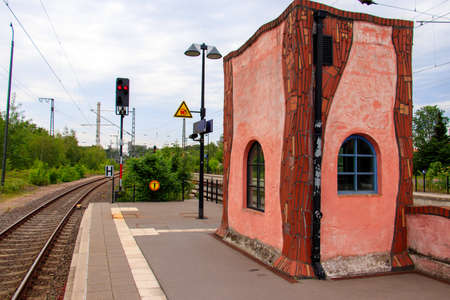 A beautiful shot of a red building near a train track surrounded by beautiful green treesの写真素材