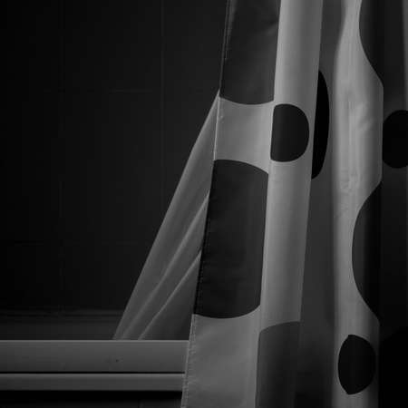 A greyscale shot of white curtain with big black spots on dark backgroundの写真素材