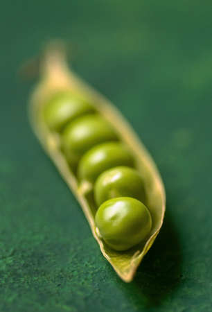 A vertical selective focus shot of the beans of a snap pea with a green blurred backgroundの写真素材