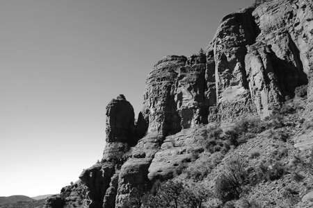 A greyscale of rocks covered in grass with blurry hills on the backgroundの写真素材