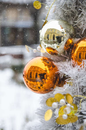 A closeup of Christmas decorations on a tree covered with snowflakes with a blurry backgroundの写真素材