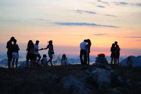 A beautiful shot of human silhouettes hanging out with couples under the breathtaking sunset skyの写真素材
