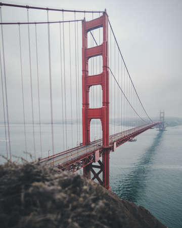 A vertical shot of the golden gate bridge under a cloudy skyの写真素材
