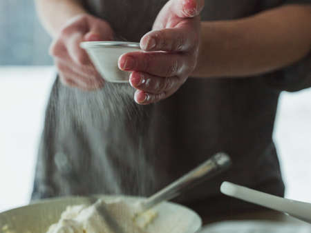 The  cook pouring the flour into the dough with a strainer - perfect for a food blog or a recipe articleの写真素材