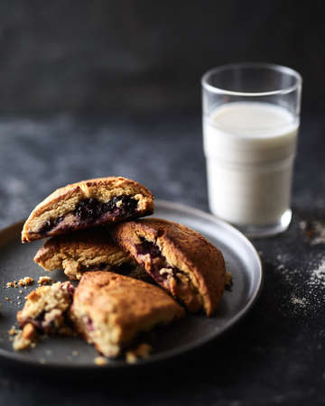A vertical shot of cookies with a berry jam and a glass of milk with a blurred backgroundの写真素材