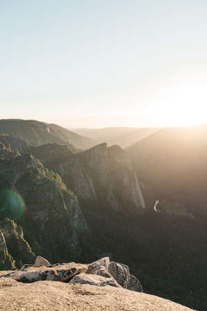 A vertical breathtaking scenery of the sun rising over a rock formation covered in greeneryの写真素材