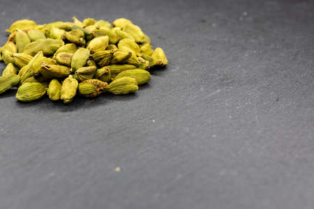 Small pile of cardamon pods on top of a black slate backgroundの写真素材