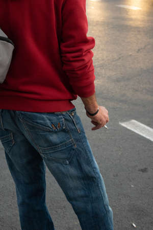 A vertical shot of a person standing on the street smoking a cigaretteの写真素材