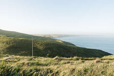 A high angle shot of hills covered in the greenery surrounding the oceanの写真素材