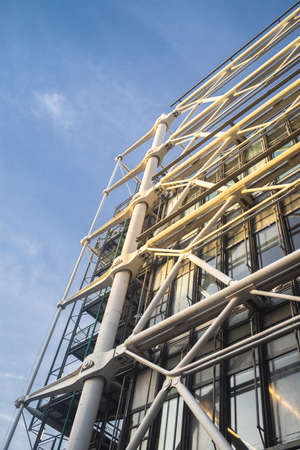 A low angle view of modern building construction under a blue sky and sunlightの写真素材