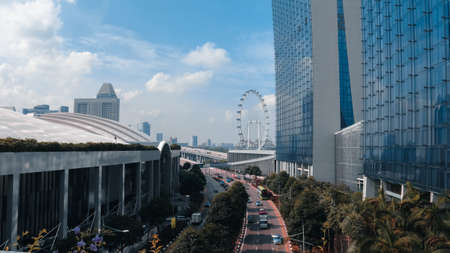 A wide shot of cars driving on the road in the middle of buildings under a blue skyの写真素材