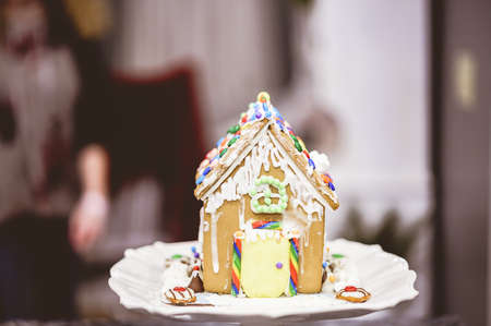 A delicious and decorated gingerbread house  on the table with a blurred backgroundの写真素材