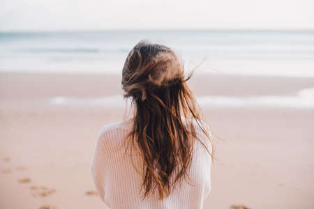 A lonely female walking on a beach in Portugal on a sunny dayの写真素材