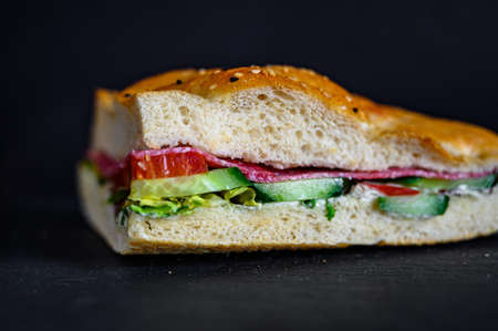 A closeup shot of a sandwich with ham on a dark surface - perfect for a food blog or menu usageの写真素材