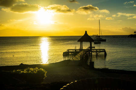 A wooden pier in the ocean in Mauritius during the sunsetの写真素材