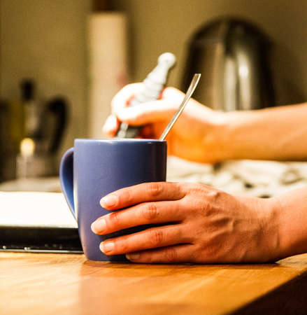 A closeup shot of a person holding its coffee on a wooden surface