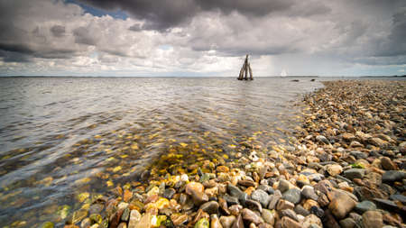 A high angle closeup shot of stones on the seashore with the calm sea on the backgroundの写真素材