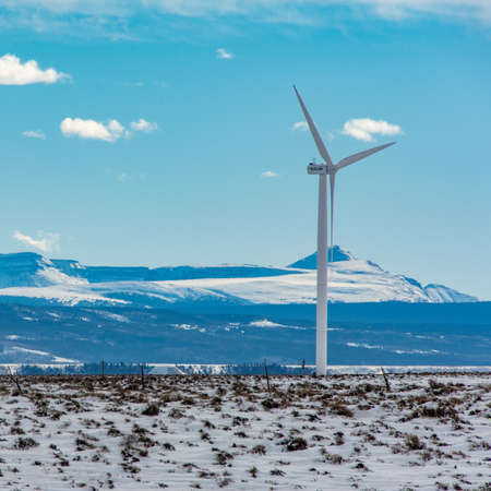A windmill standing in a field covered in white snow touching the skyの写真素材